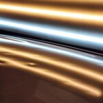 A close up of hail damage on the roof of a white car using a specialized PDR light.