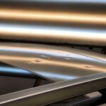 Hail Dents on a Silver car appear like dimples under a specialized hail dent (PDR) light